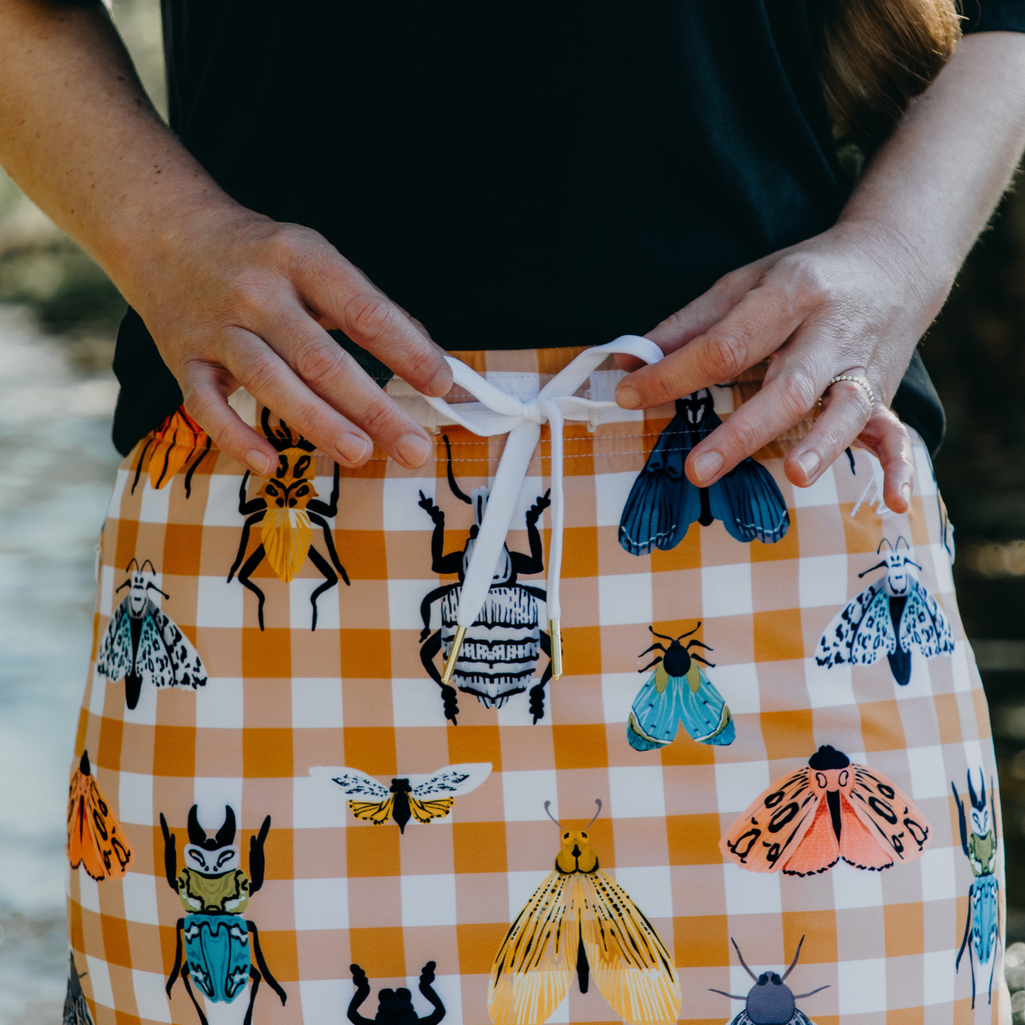 
                  
                    Person wearing a skirt with insect pattern and checkered design.
                  
                