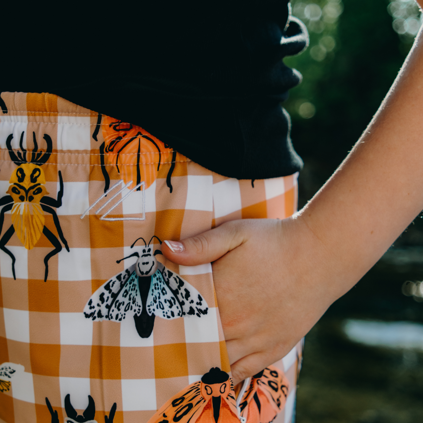 
                  
                    Person wearing a skirt with insect patterns and a checkered design.
                  
                