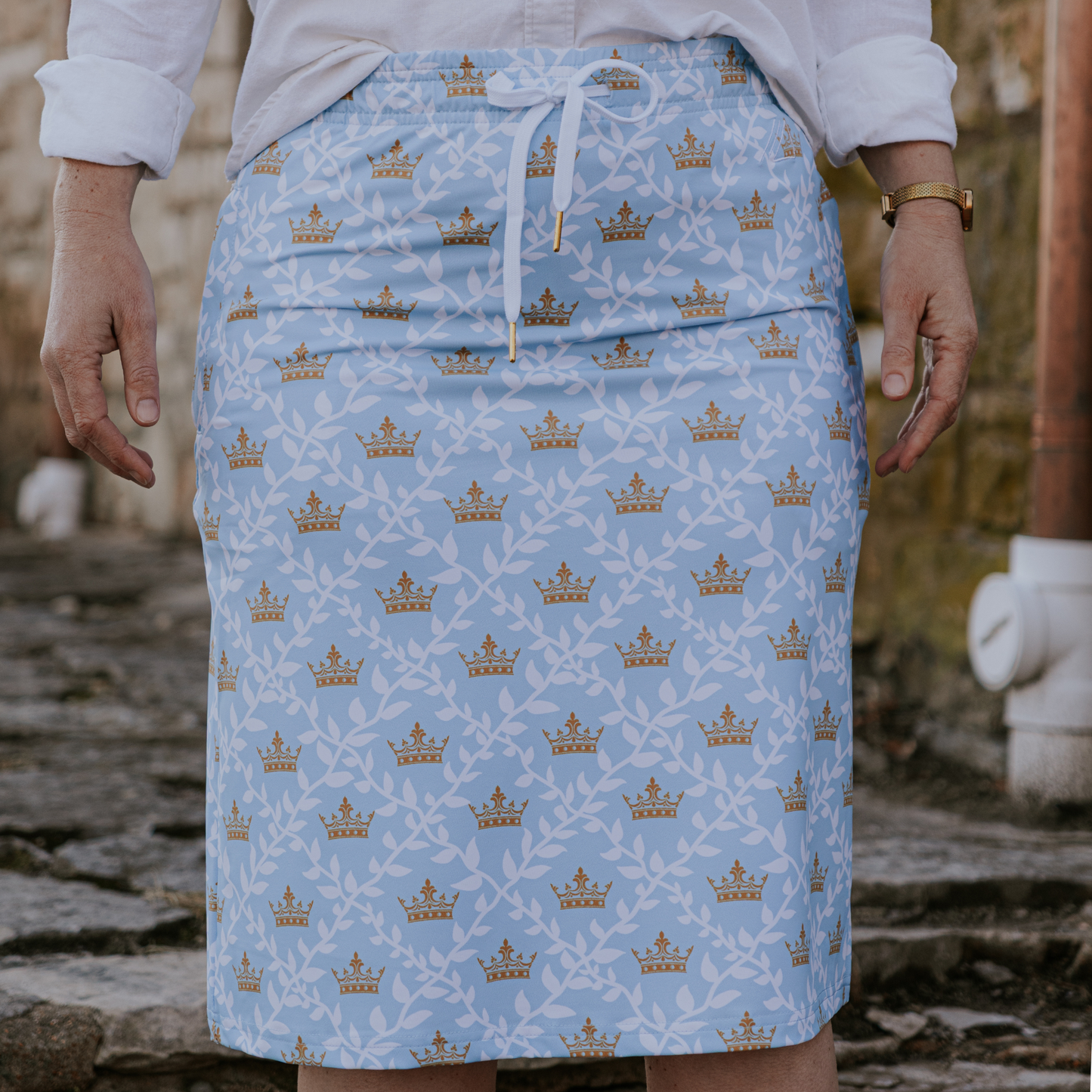 
                  
                    Person wearing a blue skirt with gold patterns on a stone surface
                  
                