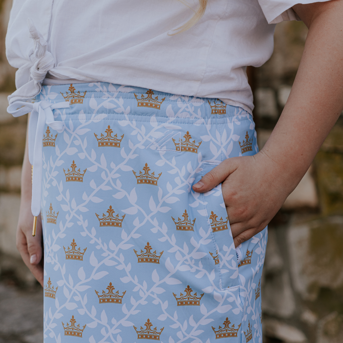 
                  
                    Person wearing a light blue skirt with gold crown patterns.
                  
                
