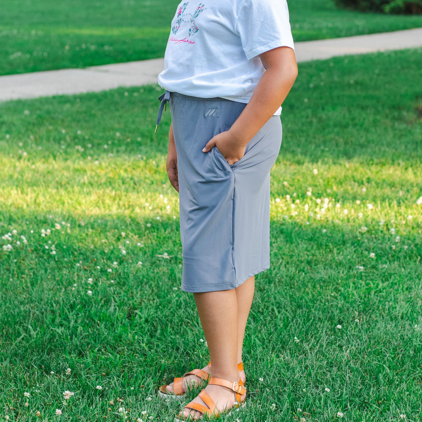 Kid wearing gray skirt and a light blue shirt standing on grass