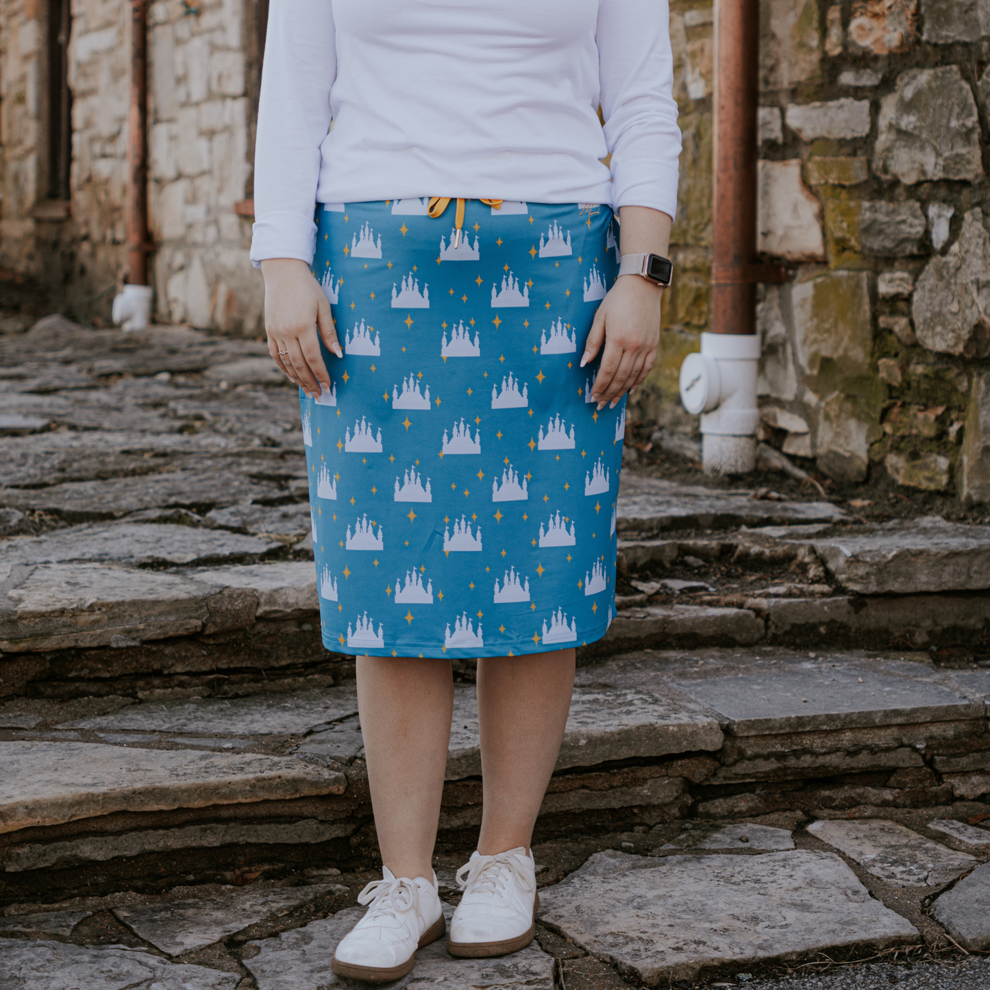 Person wearing a blue skirt with castle pattern standing on stone steps.