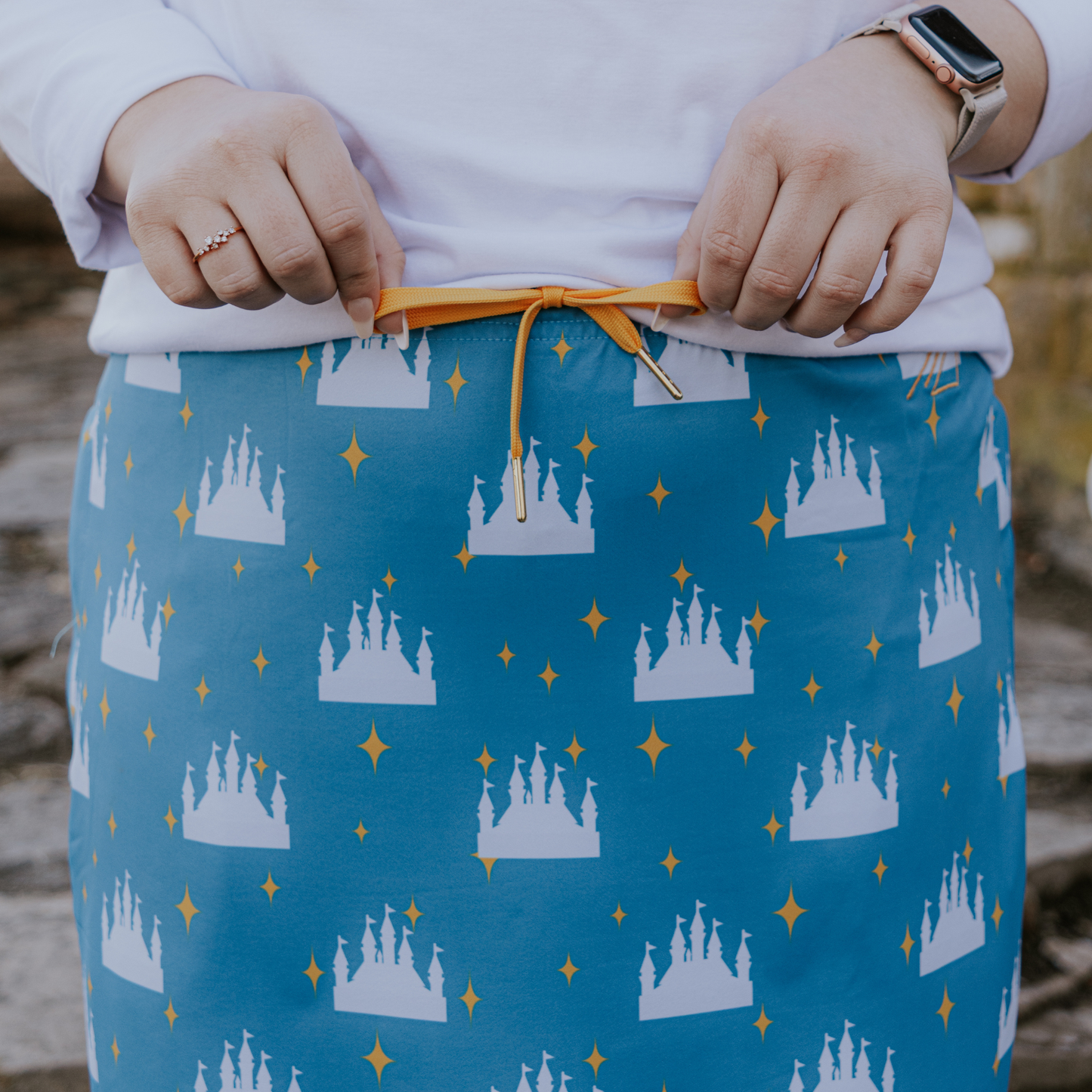 
                  
                    Person wearing a blue skirt with castle pattern and orange drawstring.
                  
                