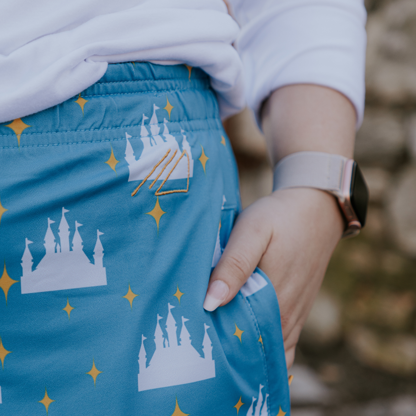 
                  
                    Blue skirt with castle and star patterns worn by a person, blurred natural background
                  
                
