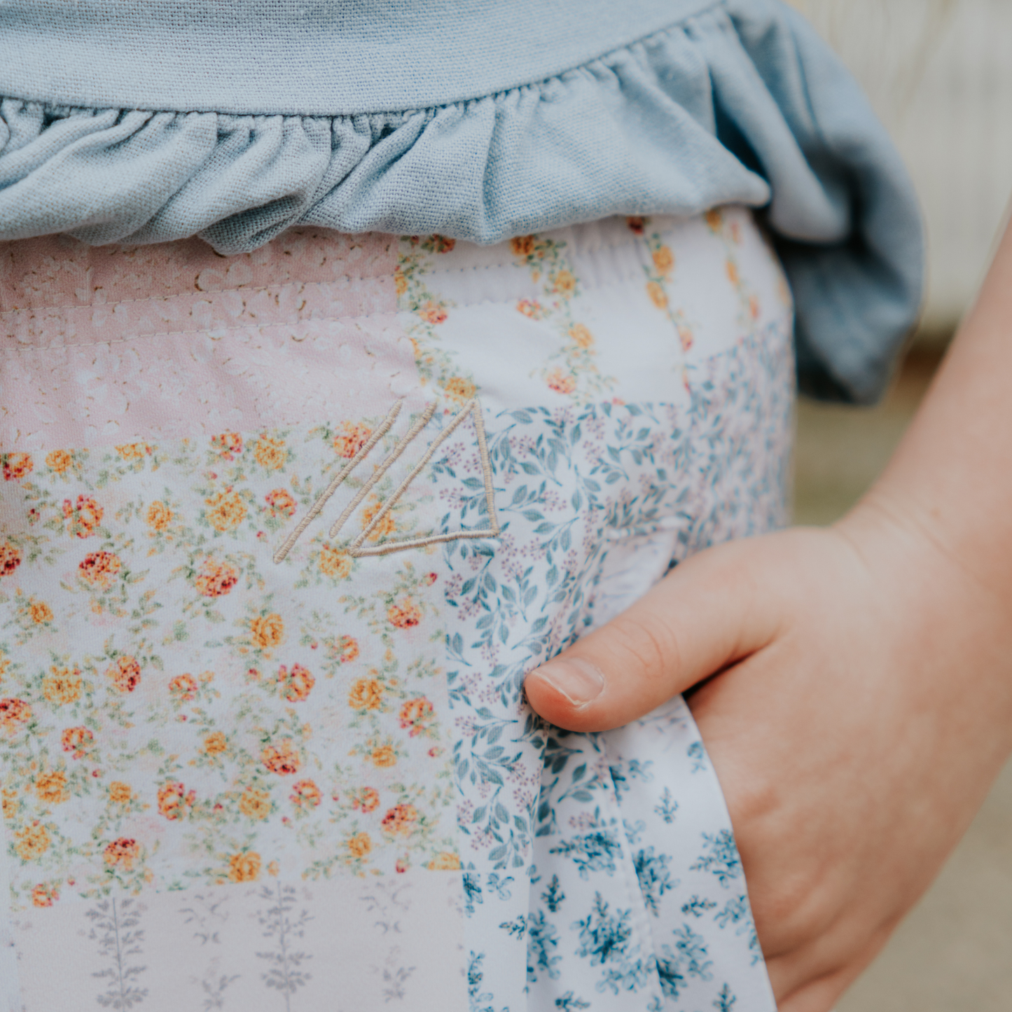 
                  
                    Close-up of a person wearing a floral skirt with a blue top, focusing on the fabric details.
                  
                
