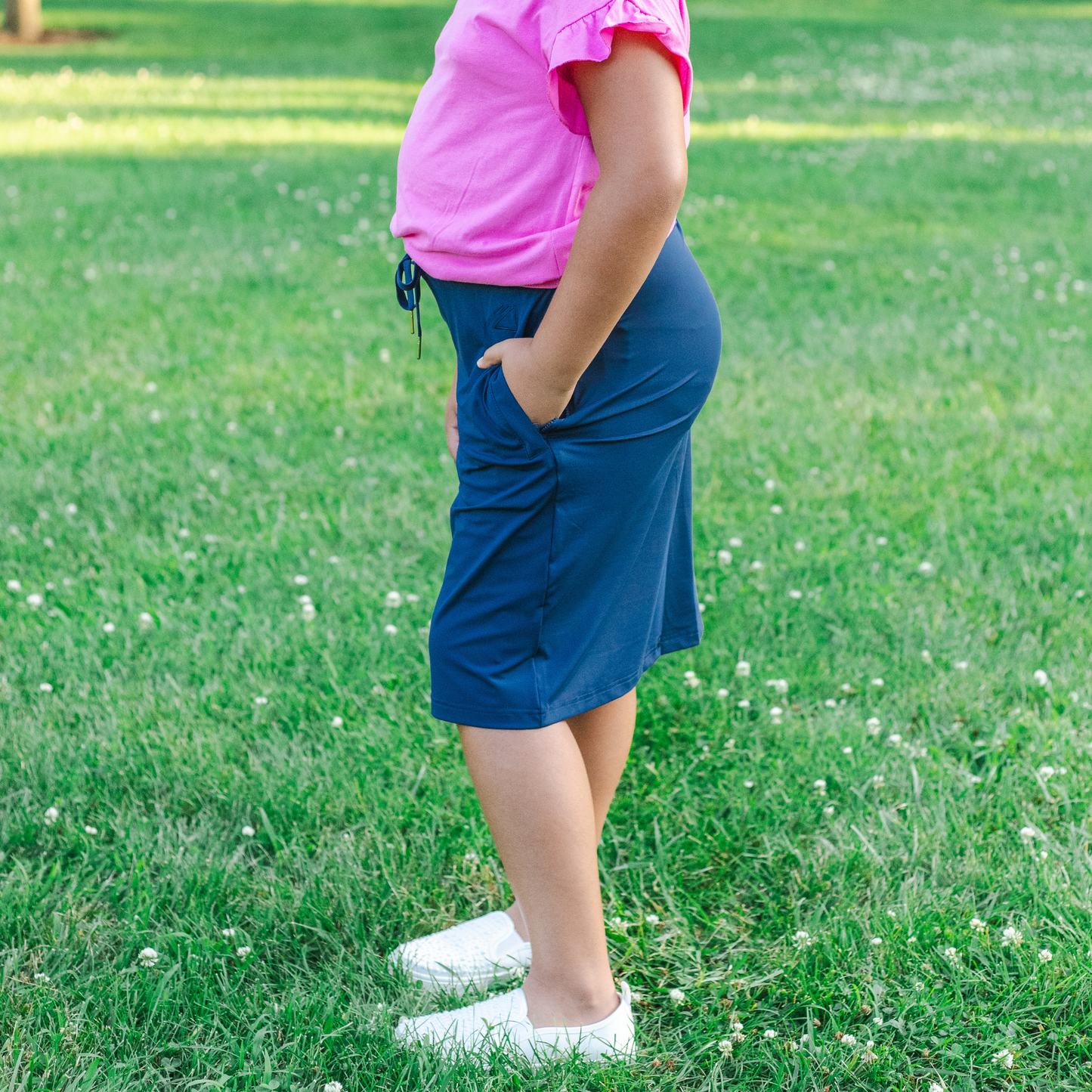 Kid wearing a pink shirt and blue skirt standing on grass