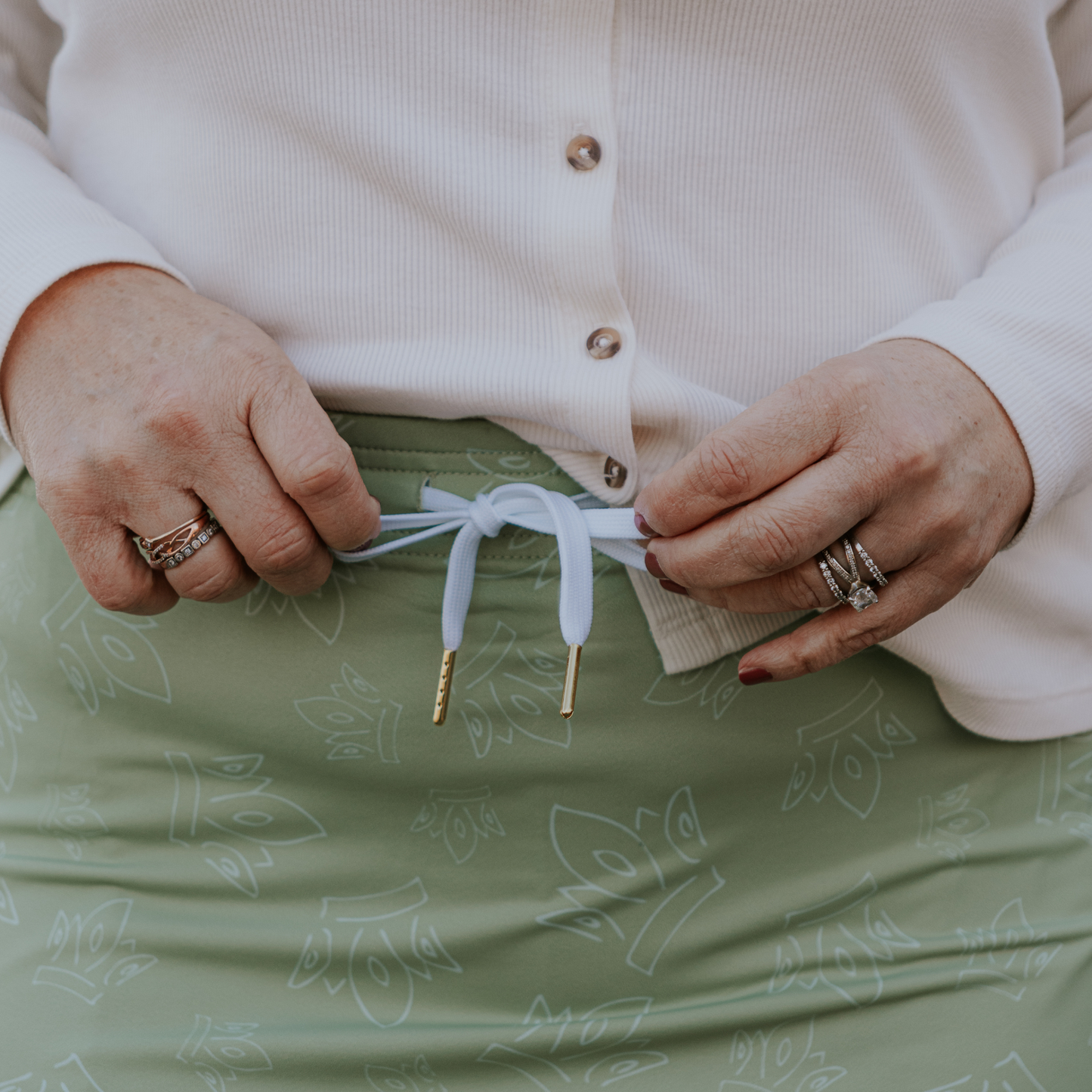 
                  
                    Person tying a drawstring on a green patterned skirt
                  
                