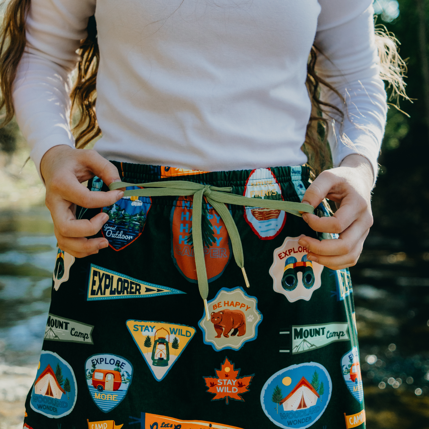 
                  
                    Person wearing skirt with drawstrings with outdoor-themed patches by a body of water.
                  
                