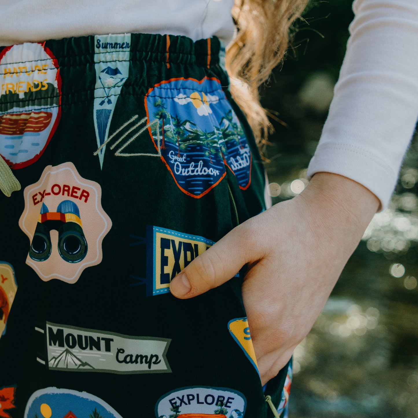 
                  
                    Person wearing dark skirt with various patches and logos, outdoors.
                  
                
