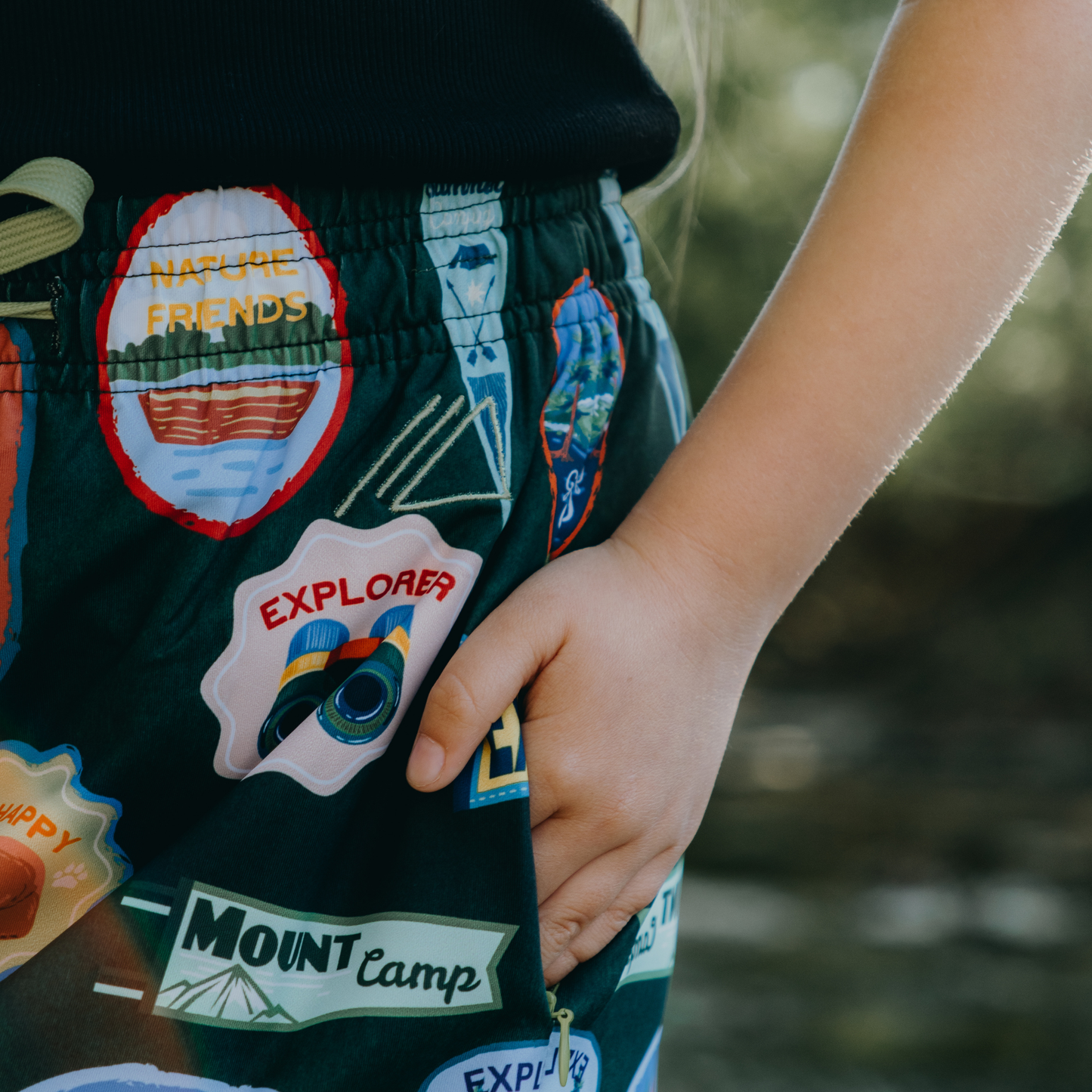 
                  
                    Children's skirt with various patches and text on a blurred natural background
                  
                