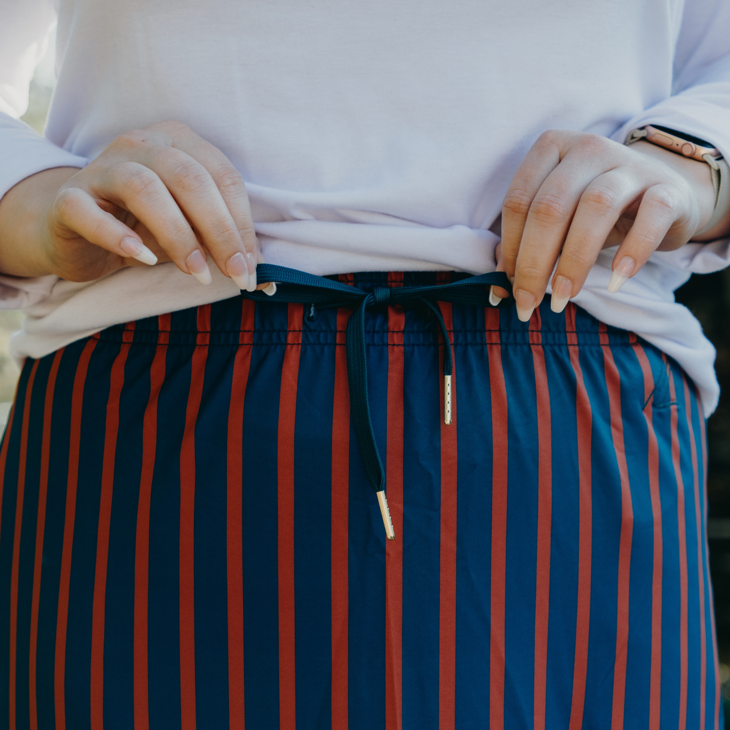 
                  
                    Person wearing a white top and blue and orange striped skirt with drawstring.
                  
                