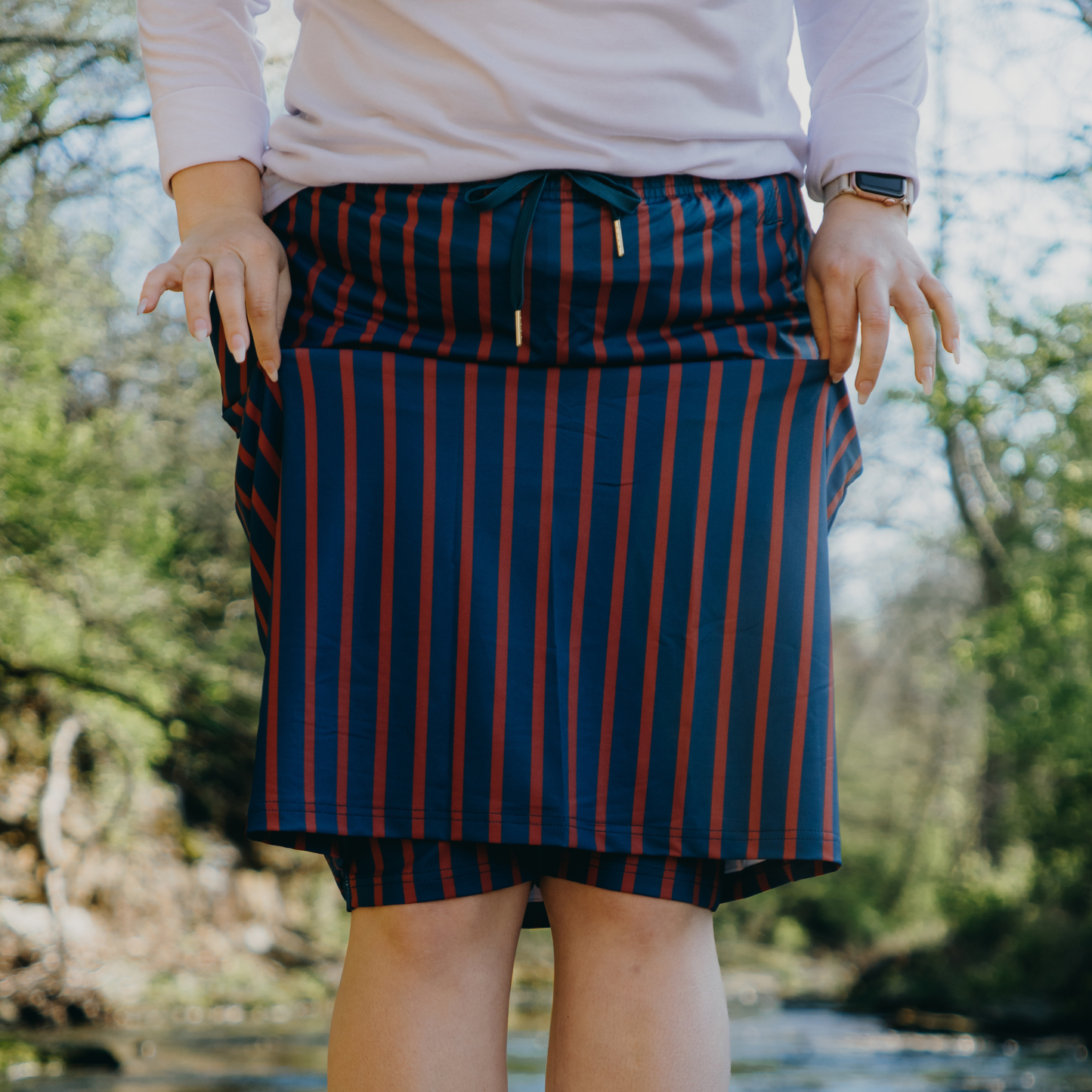 
                  
                    Person wearing a blue and orange striped skirt with a blurred natural background
                  
                