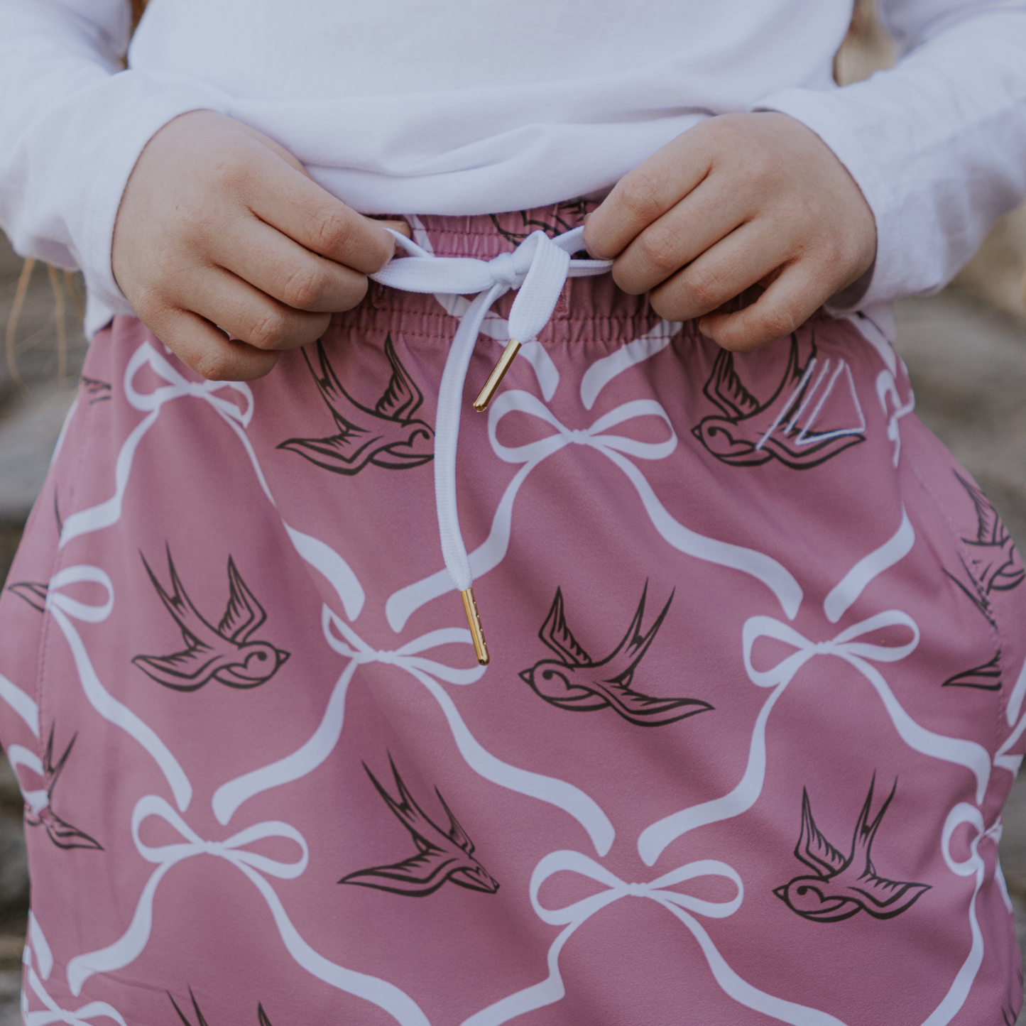 
                  
                    Pink skirt with bird and bow pattern worn by a person.
                  
                