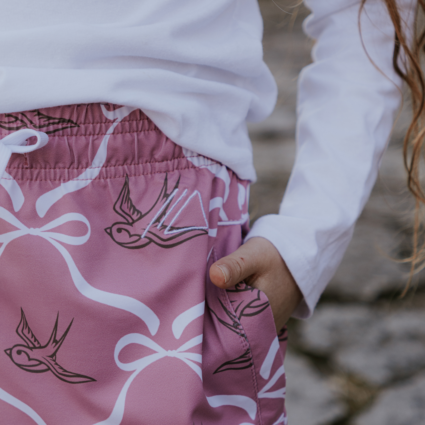 
                  
                    Pink skirt with bird patterns worn by a child, blurred background
                  
                