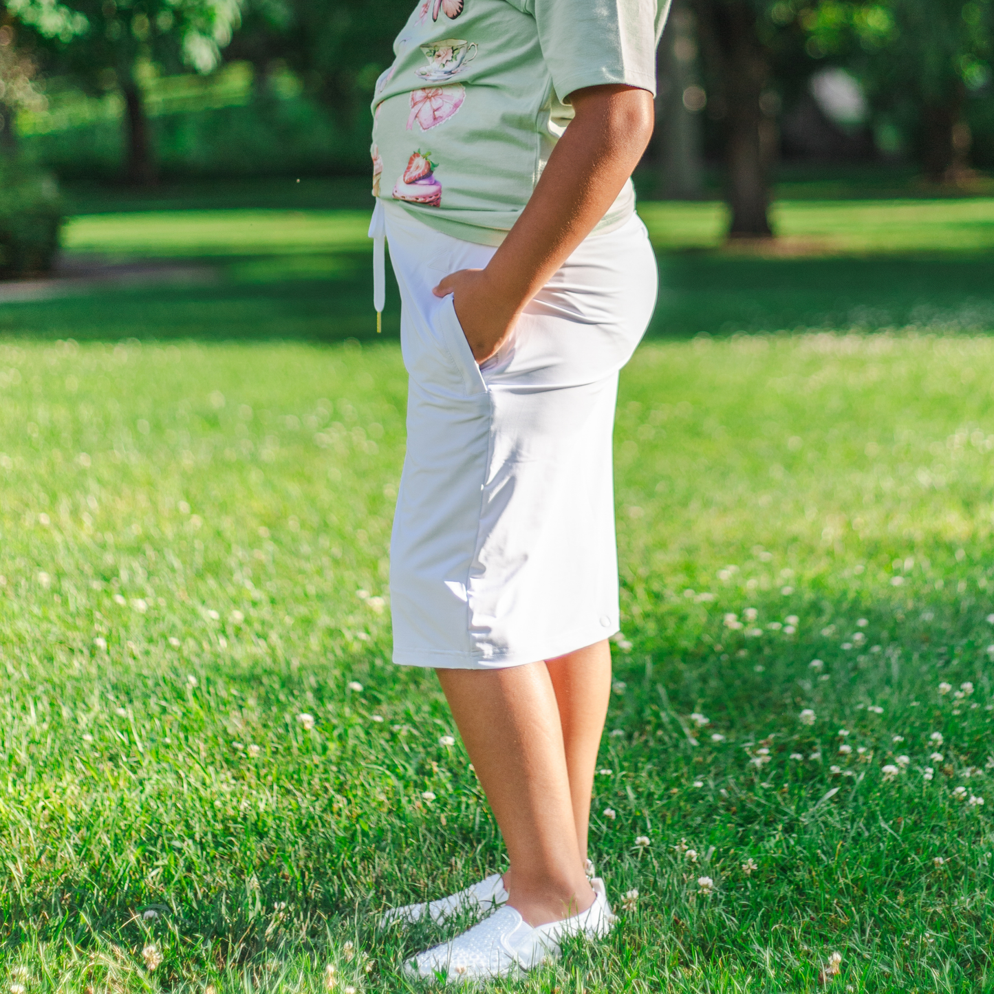 Kid wearing a light green shirt and white skirt standing on grass