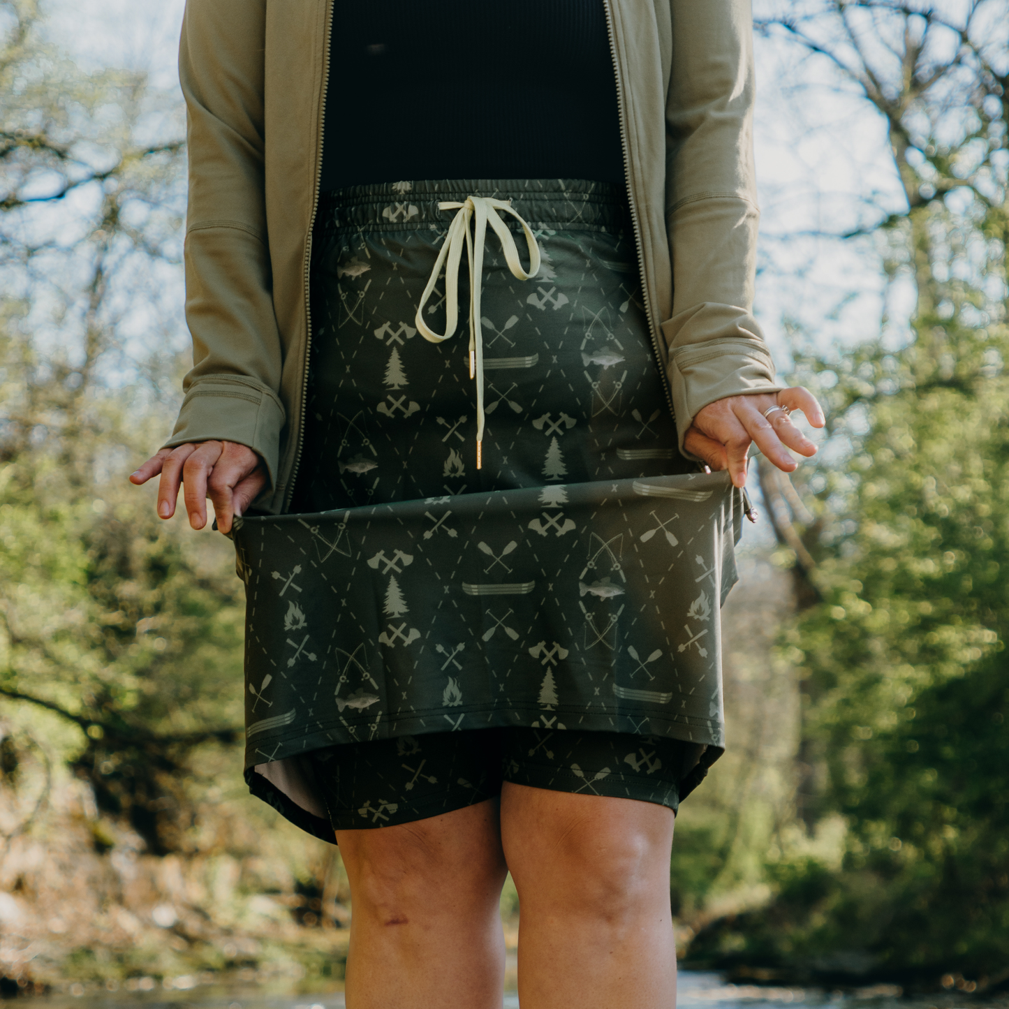 
                  
                    Person wearing a patterned skirt outdoors with trees in the background
                  
                
