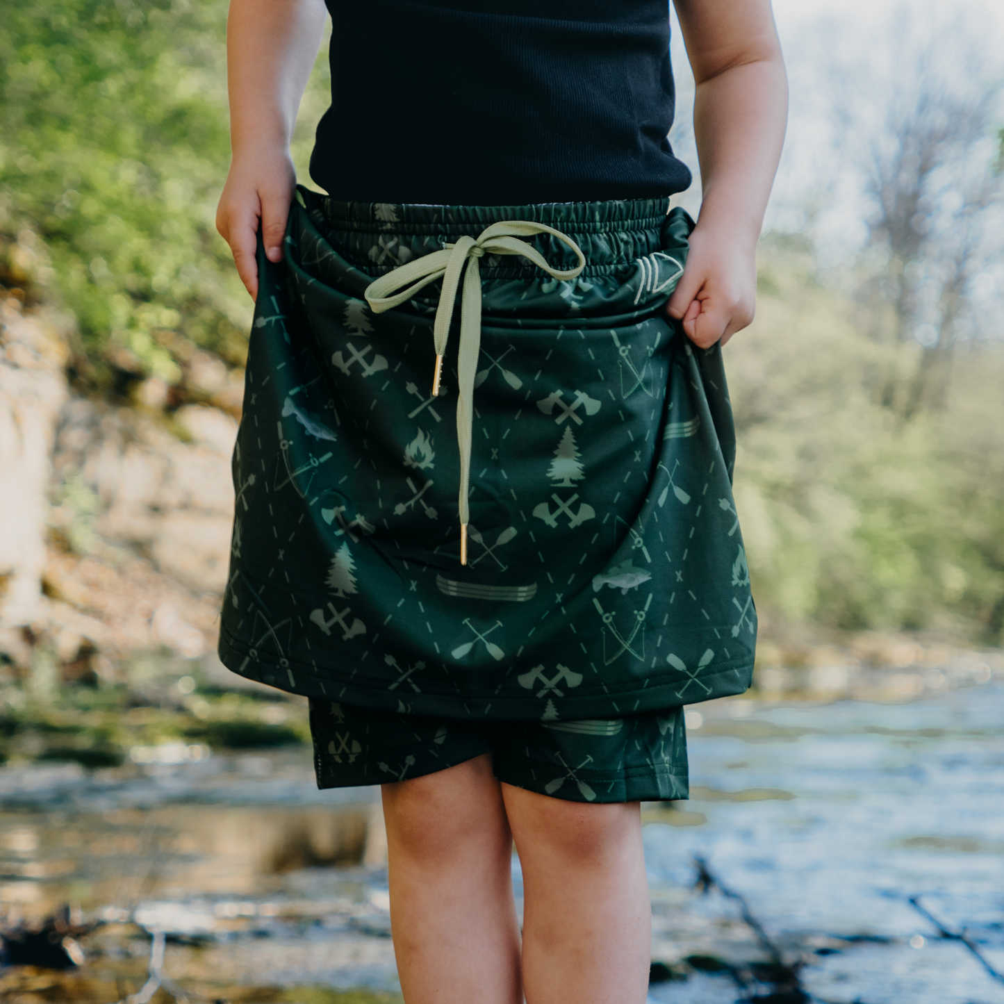 
                  
                    Kid wearing a green patterned skirt with a blurred natural background
                  
                