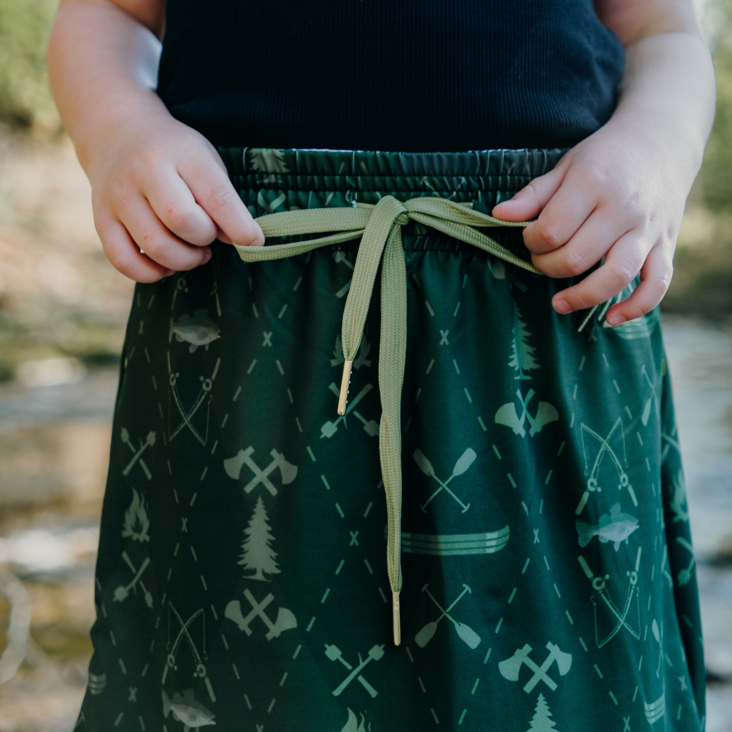 
                  
                    Kid wearing a green patterned skirt with a blurred natural background
                  
                